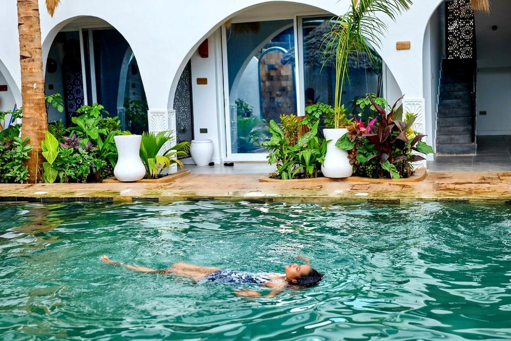 a man laying in the water in a swimming pool at Nyota Boutique Hotel Zanzibar in Nungwi