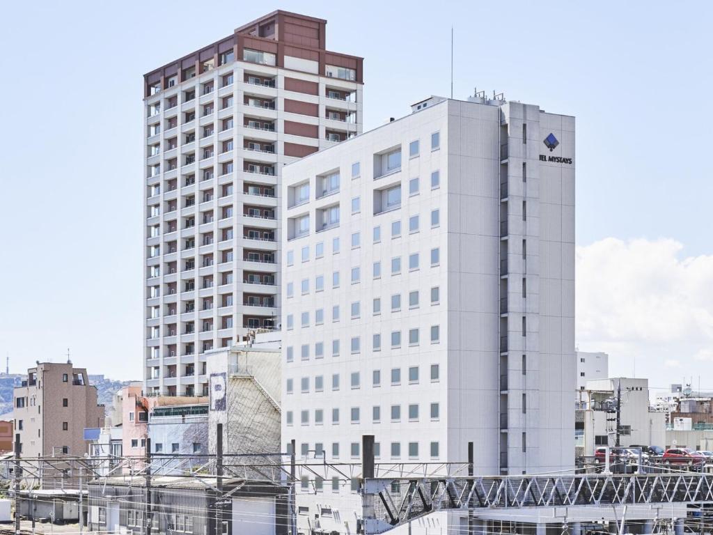 a tall white building in the middle of a city at HOTEL MYSTAYS Shimizu in Shizuoka