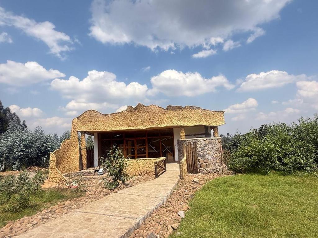 a small stone building with a straw roof at Gahinga Community Lodge in Kinigi