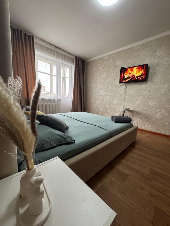 a bedroom with a bed with a fire painting on the wall at N40 Apartment in Pavlodar