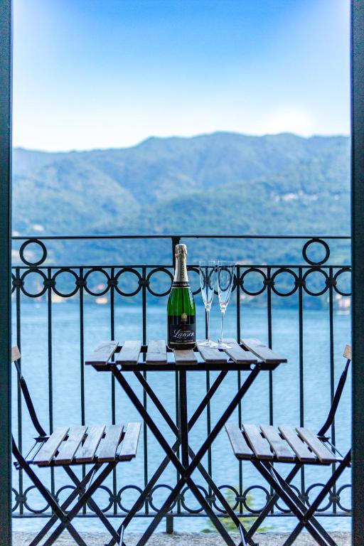 a bottle of wine sitting on a table on a balcony at Simo House Stunning Lake View Balcony AC in Carate Urio