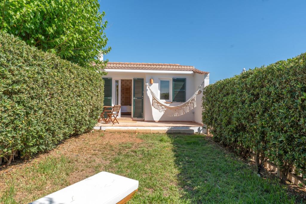 a house with a hammock in front of a hedge at Villas 19 Estrellas in Cala en Bosc