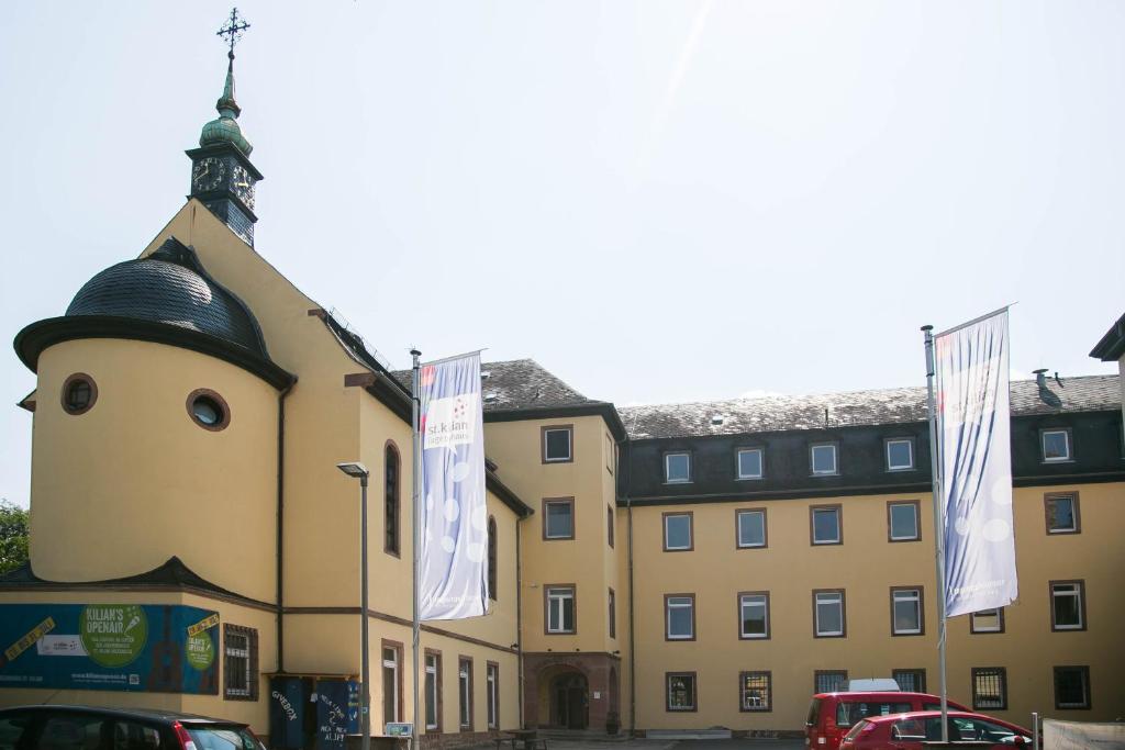 a large yellow building with flags in front of it at Jugendhaus St. Kilian in Miltenberg