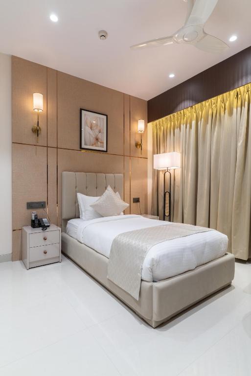 a bedroom with a large white bed and a white floor at Hotel Lohara Inn in Chandrapur
