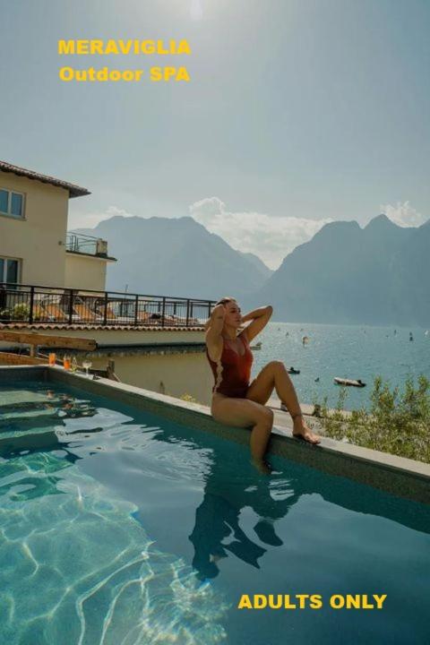a woman sitting on the edge of a swimming pool at Hotel Paradiso Conca d'Oro in Nago-Torbole