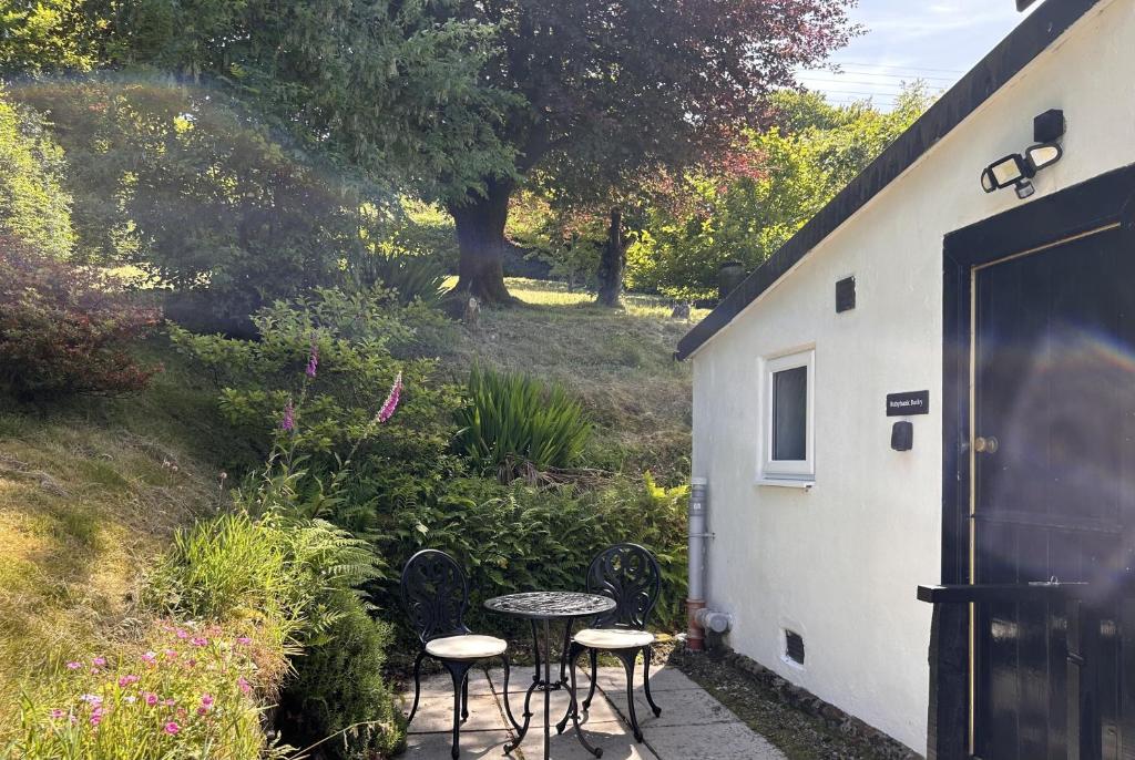 a patio with a table and chairs next to a building at Rubybank Bothy, overlooking Loch Fyne in Strachur