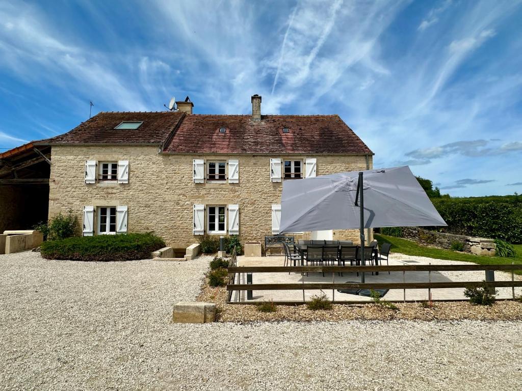 a table and an umbrella in front of a building at Valfermet 5 personnes in Mauvilly