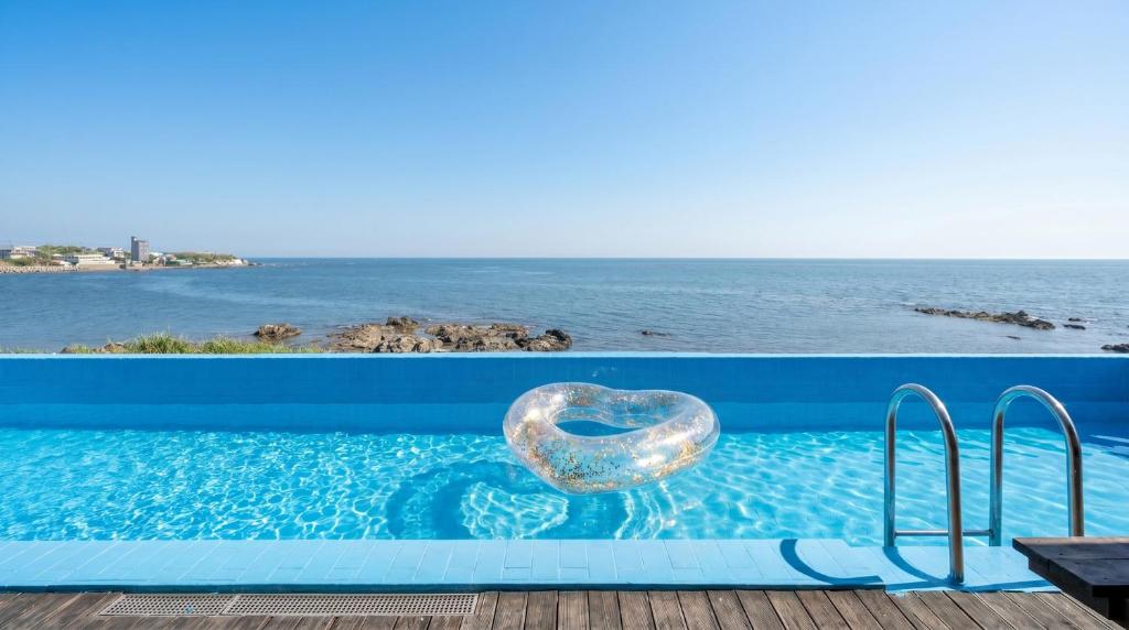 a glass heart in a swimming pool next to the ocean at Pohang Pine Wave Pension in Pohang
