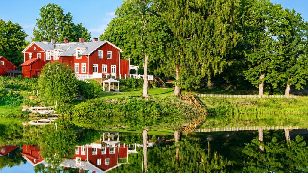 a red house and its reflection in the water at Husby Wärdshus in Dala Husby