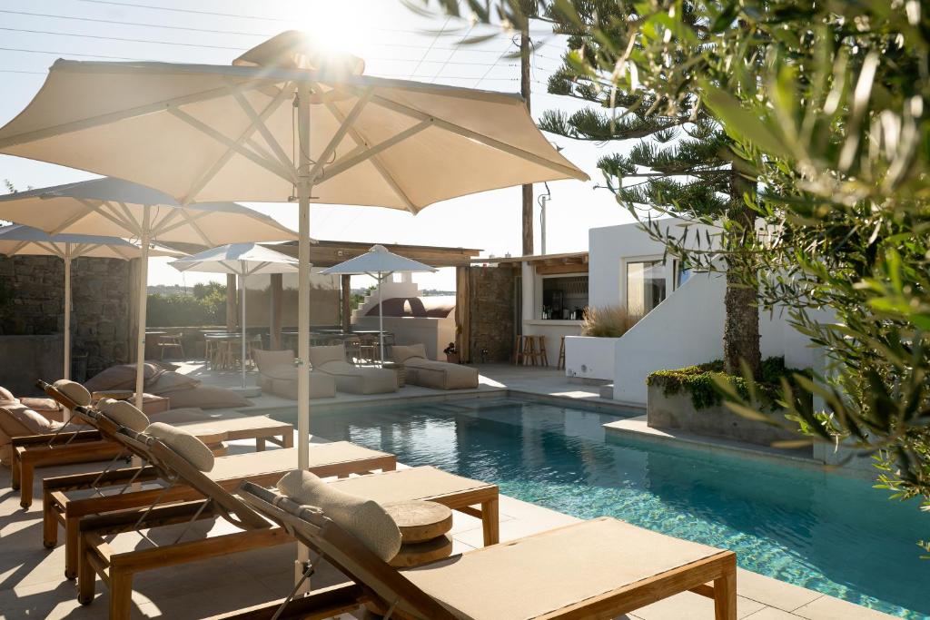 a pool with tables and chairs and umbrellas at Oliving Mykonos Luxury Suites in Klouvas