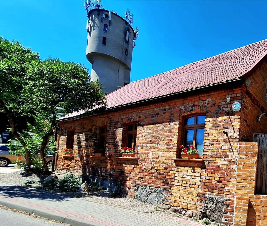 Ein Backsteingebäude mit einem Leuchtturm im Hintergrund in der Unterkunft Gordonówka in Choszczno