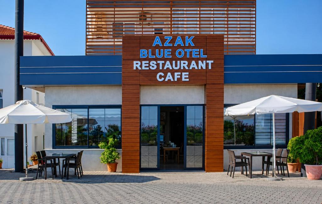 a restaurant with tables and umbrellas in front of a building at AZAK BLUE OTEL in Okurcalar