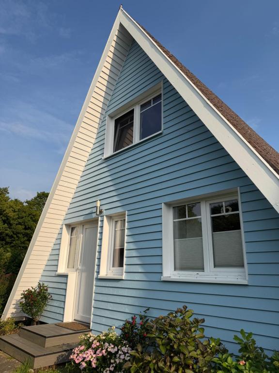 a blue house with white windows and flowers at Ferienhaus Seemöwe in Damp