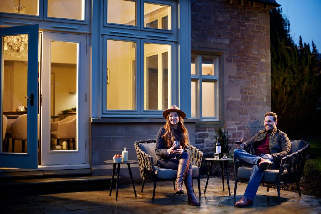 two people sitting in chairs on a patio at Roxburghe Cottages, part of Destination by Hyatt in Kelso