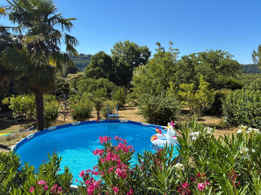 a blue swimming pool in a garden with flowers at Maisonette paisible à La Roque-Gageac in La Roque-Gageac