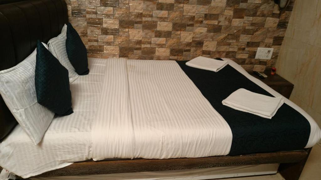 a bed with black and white sheets and pillows at Hotel Oliver in Mumbai