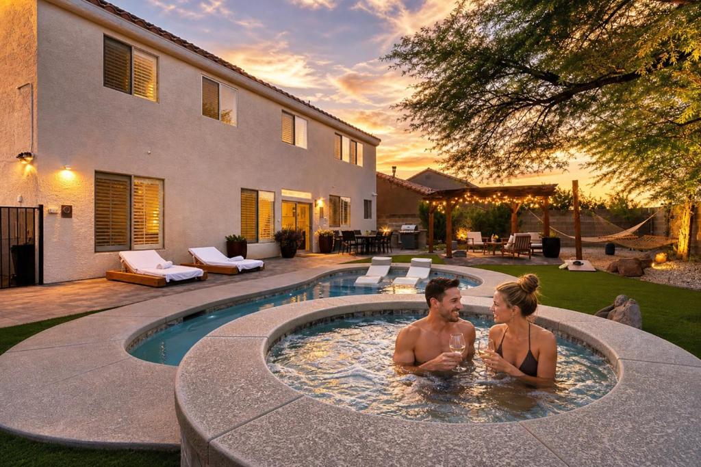 a man and a woman sitting in a swimming pool at Luxury and Harmony in a 6BR Dream Villa; Pool, Hot Tub, Game room, Near the Las Vegas Strip in Las Vegas