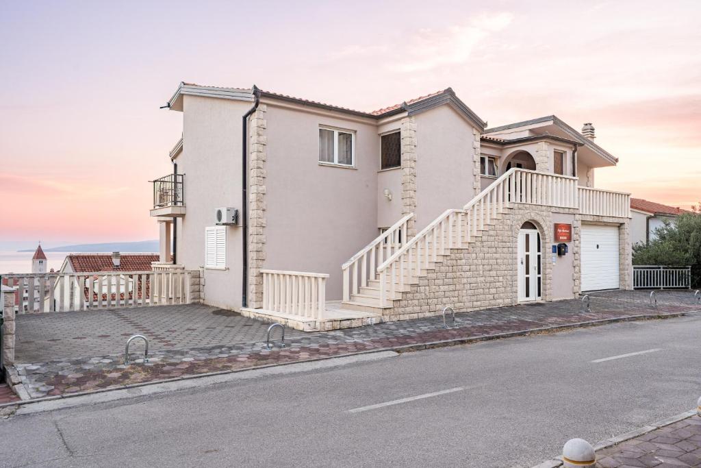 a white house with stairs on a street at Apartments Amaris in Promajna