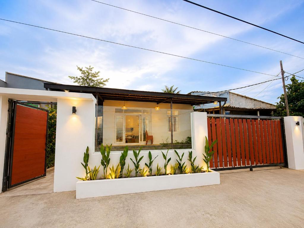 a house with a red gate and a fence at SAN HÔ Beach Homestay in Thôn Ðông Giang
