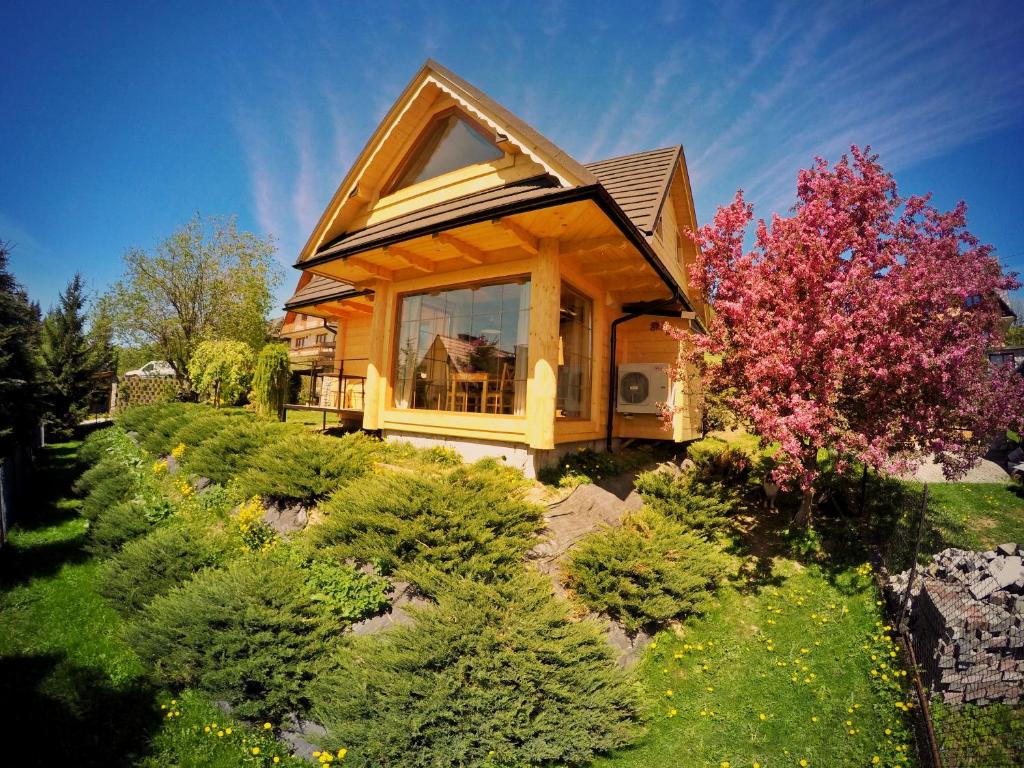 a house with a large window in the yard at Domek Pod Wierchami z Jacuzzi in Kościelisko