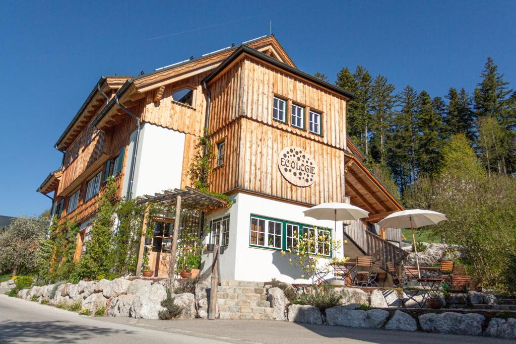 a wooden building with an umbrella in front of it at Ecologie Grundlsee in Grundlsee