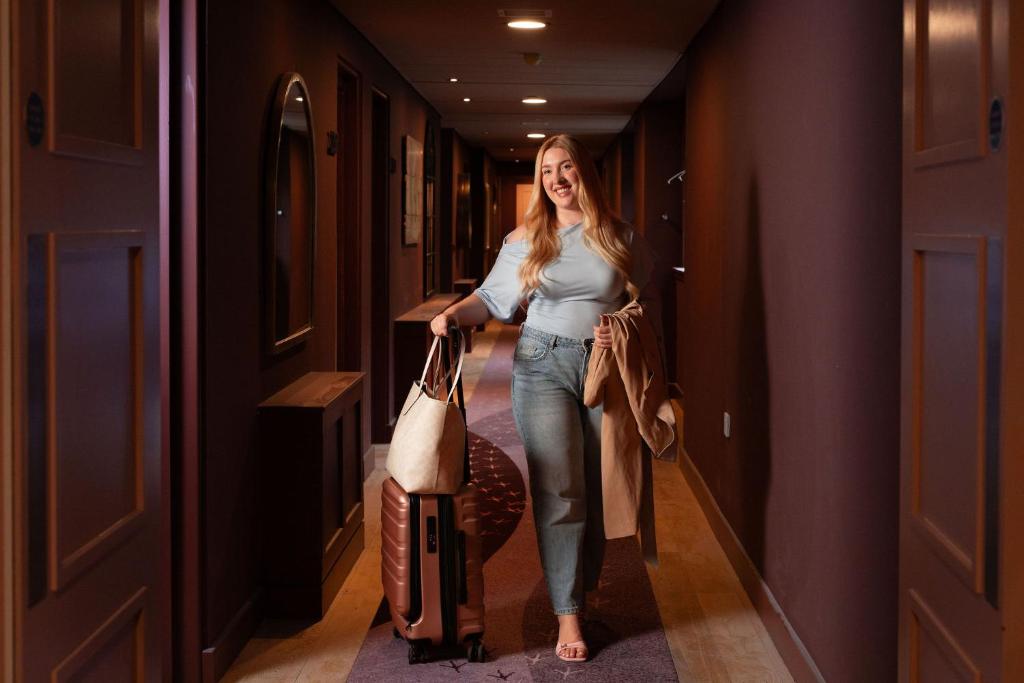 a woman walking down a hallway with her luggage at The Address Wren in Glasgow
