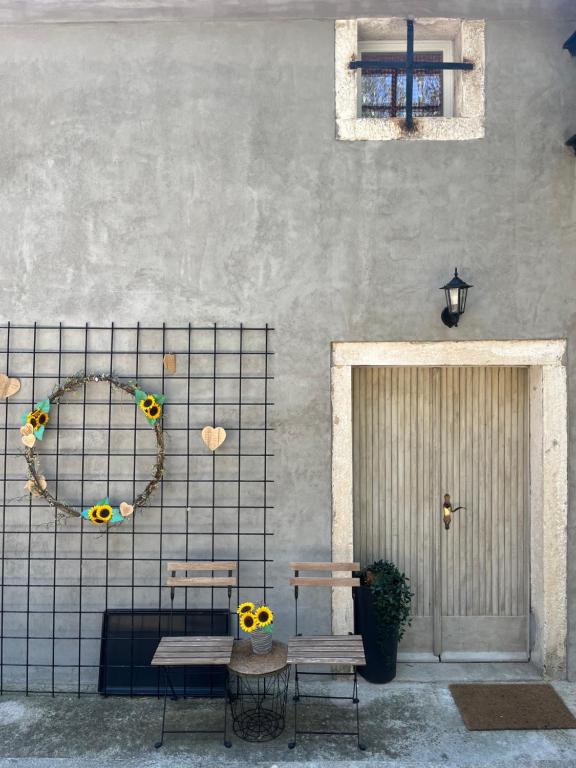 a patio with two benches and a wreath on a wall at Hramišče, Botega in Šmarje