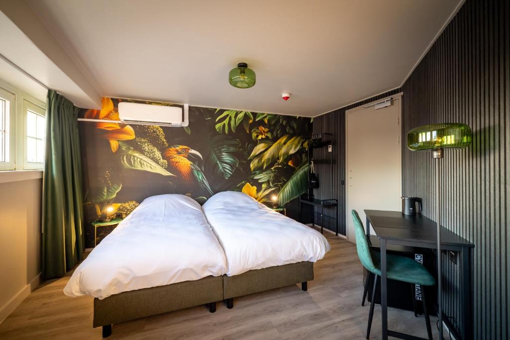 a bedroom with a bed and a table with a painting at Stadshotel Tante Annie's in Oldenzaal