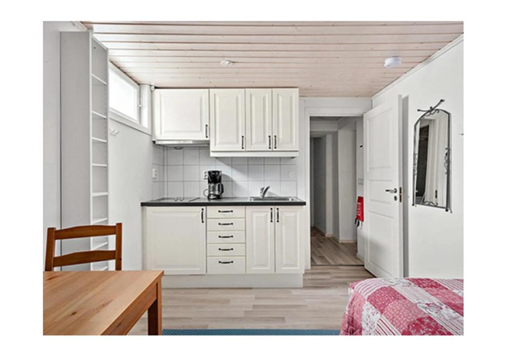 a kitchen with white cabinets and a table in a room at Central City nest in Haparanda