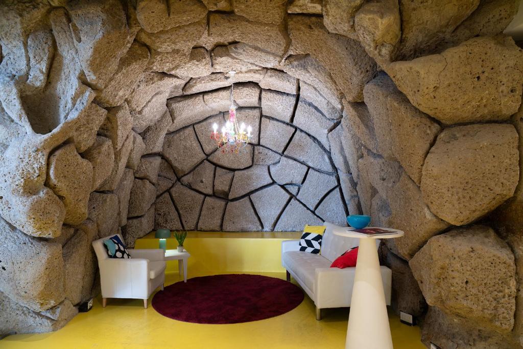 a room with a stone wall with a couch and chairs at Correra 241 Lifestyle Hotel in Naples