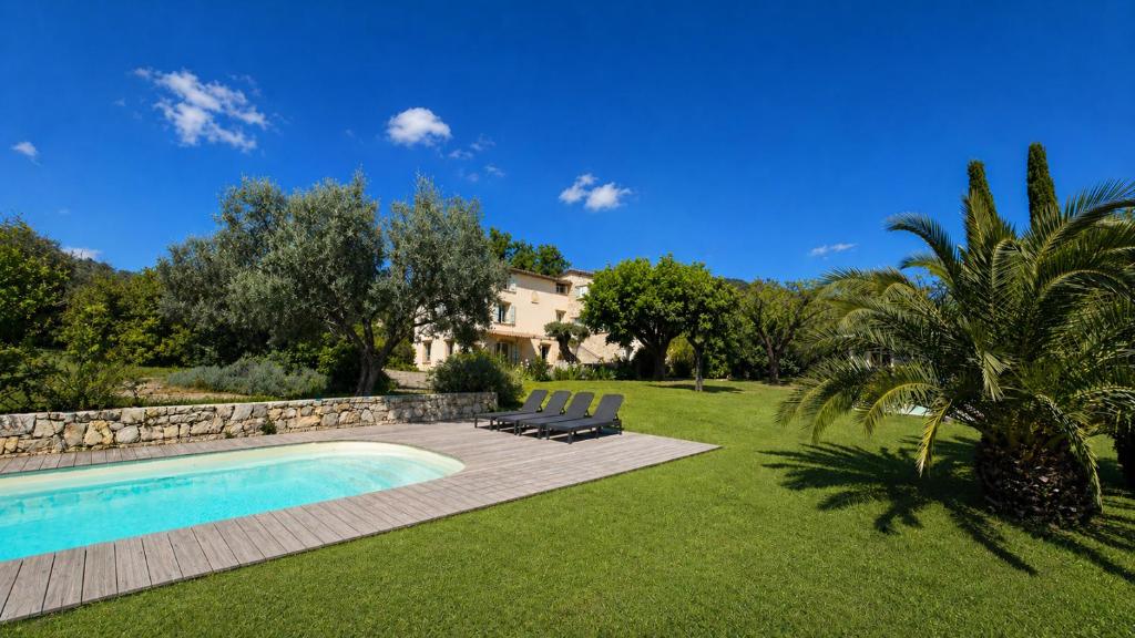 a swimming pool in a yard with chairs and a house at L'Escale Provençale in Tourrettes
