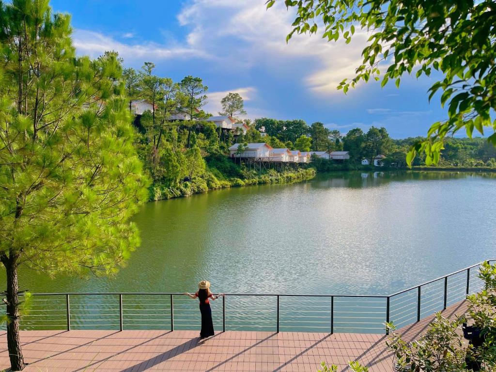 a woman standing on a walkway next to a river at La Vela Legacy Resort in Thôn Dương Xuân Hạ