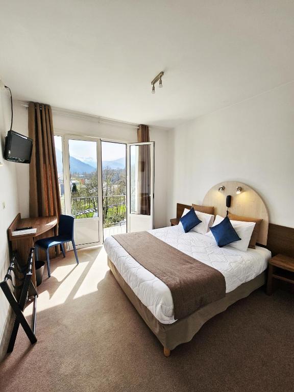 a bedroom with a large bed and a desk and window at Adonis Lourdes - Notre Dame de la Sarte in Lourdes