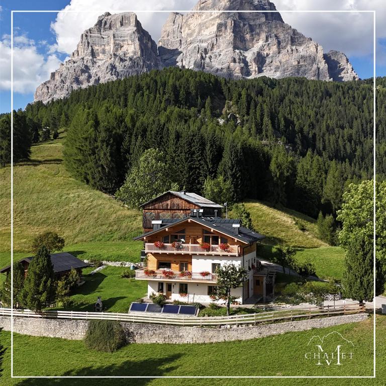 a house on a hill with mountains in the background at Chalet M in Val di Zoldo