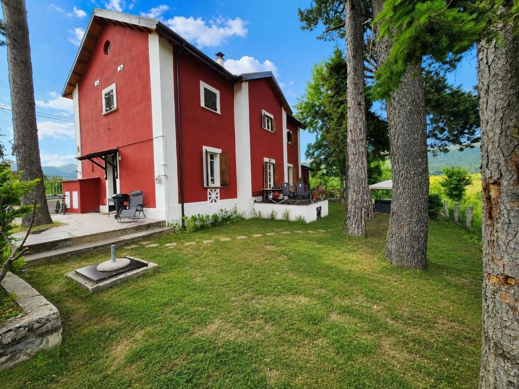 a red and white house with trees in the yard at Antico Chalet Momosa Maxi in Ovindoli