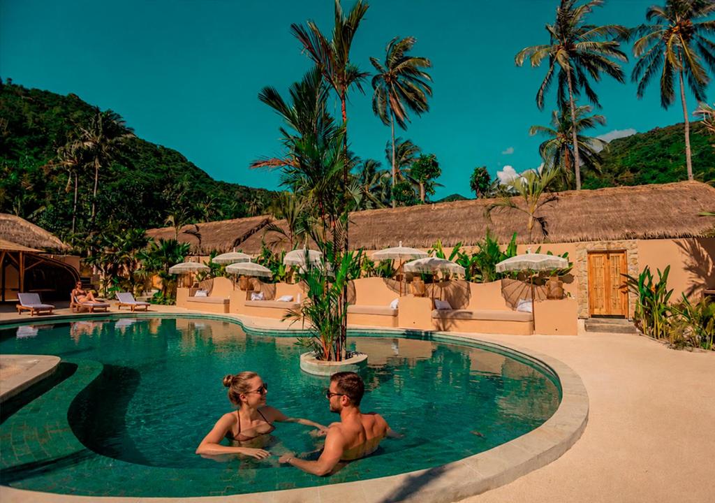 two people sitting in the swimming pool at a resort at Lombok Souls in Senggigi