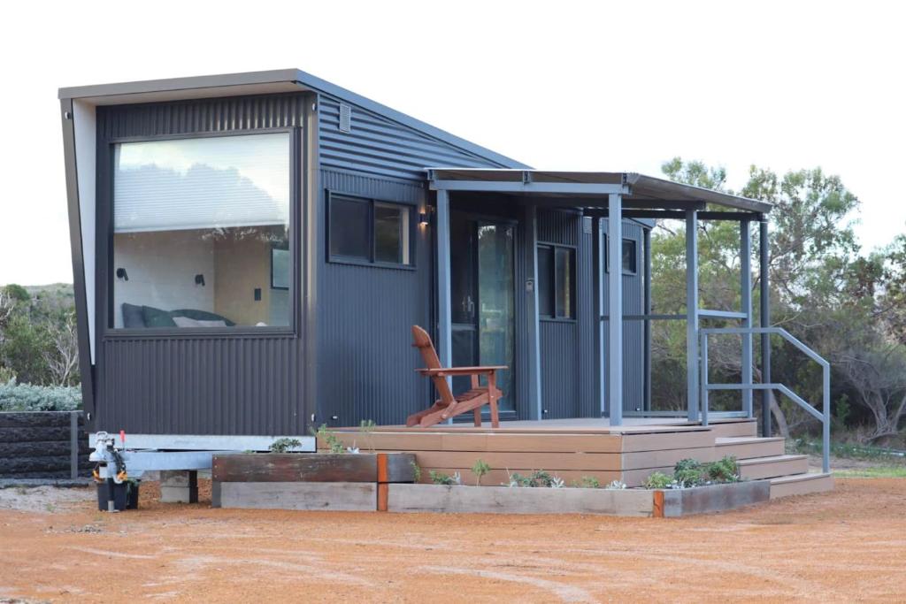 a tiny house with a large window and a staircase at Nine77 - Tiny Home Retreat in Esperance