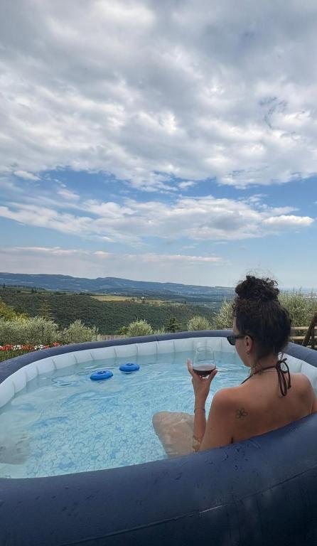 a woman sitting in a swimming pool with a glass of wine at La Terrazza in Collina in Cavalo