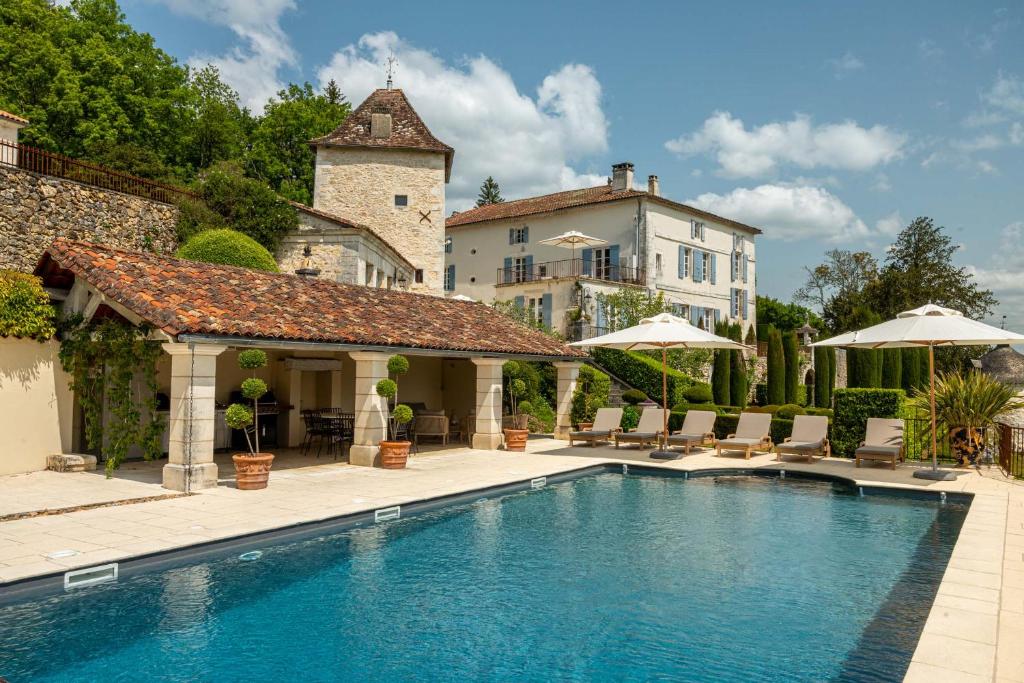 a swimming pool with chairs and umbrellas next to a building at Villa Privée avec Piscine - Lavy in Saint-Pierre-de-Côle