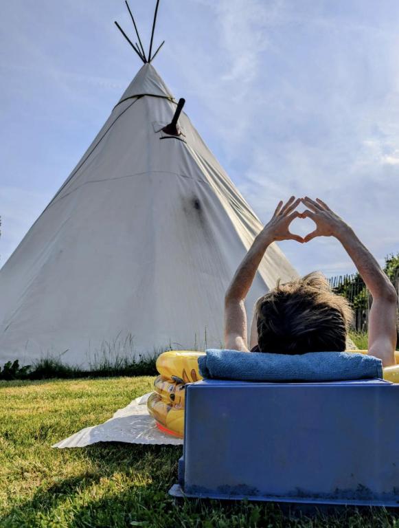 a person laying on a blanket in front of a teepee at Le tipi d'Adri in Gesves