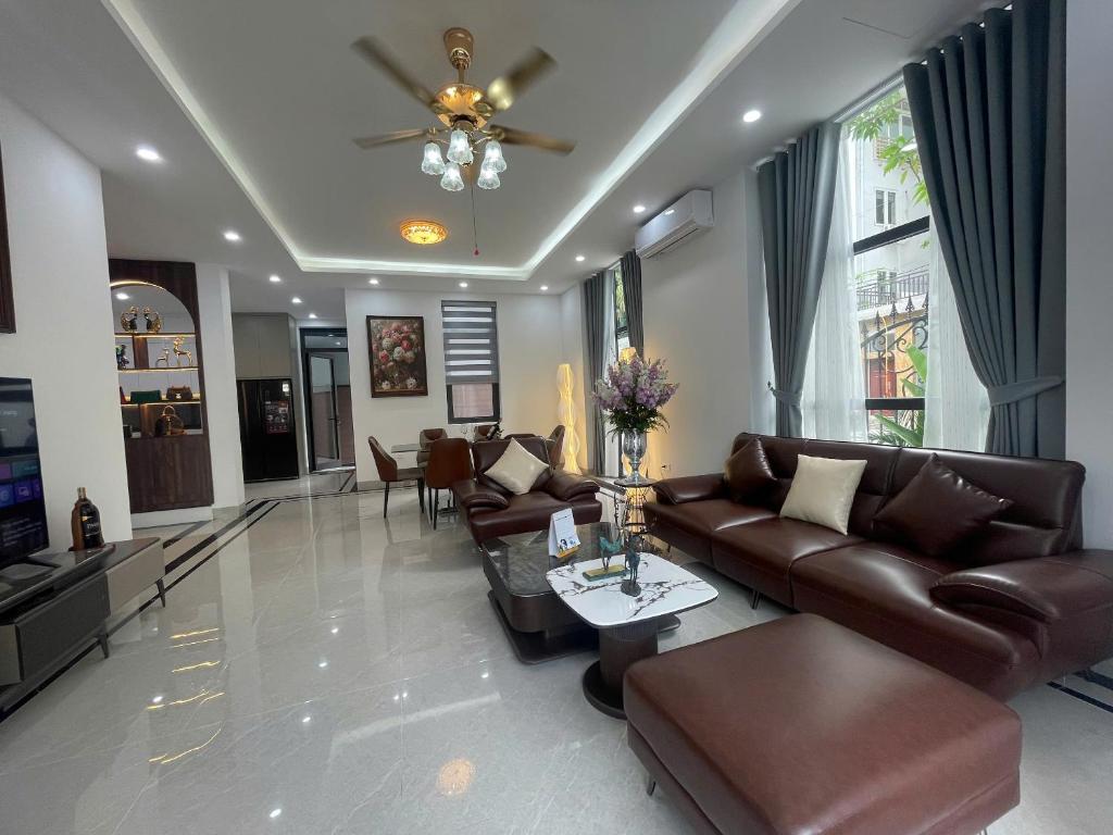 a living room with leather couches and a television at Van Khe Cozy Villa in Hà Ðông