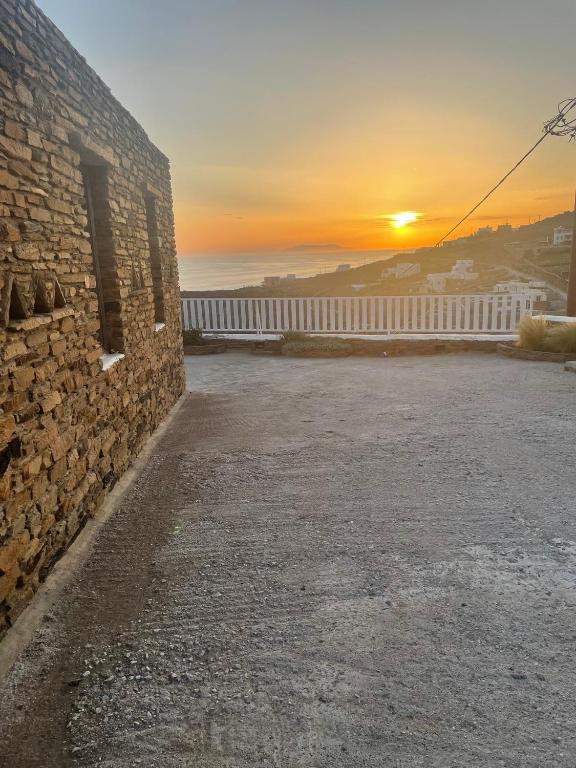 a sunset behind a brick wall with a white fence at The Sunrise Villa in Koumáros