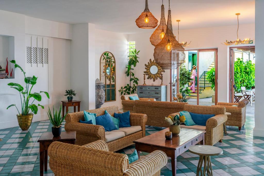 a living room with wicker furniture and blue pillows at Hotel Baia Di Puolo in Massa Lubrense