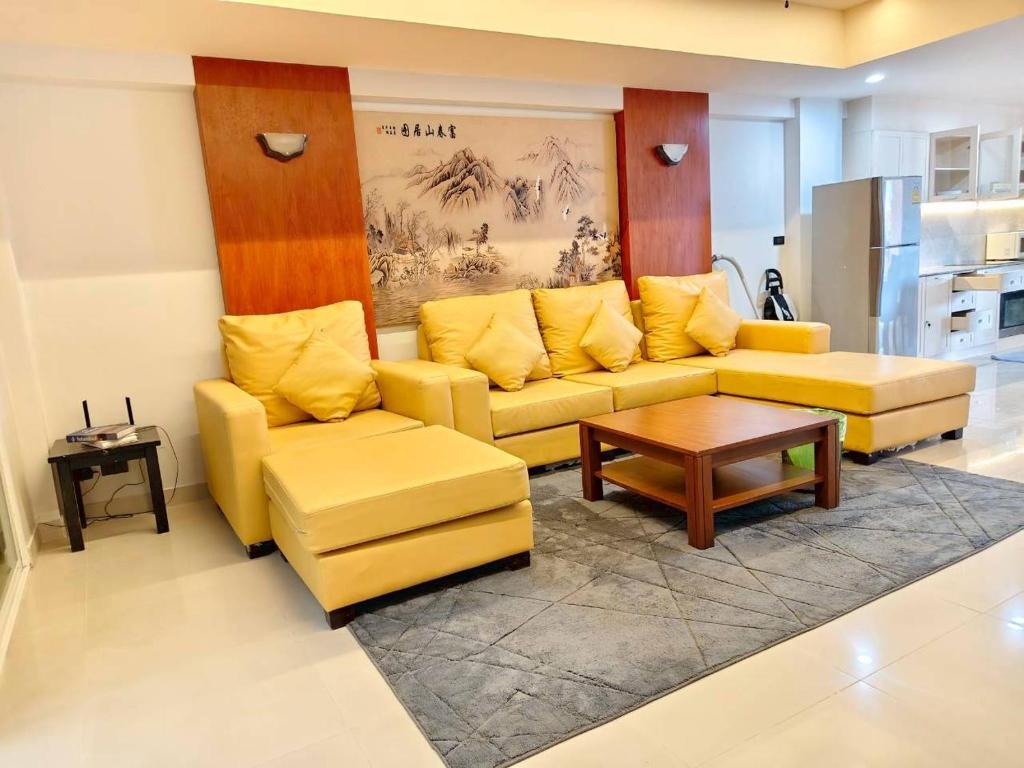 a living room with a yellow couch and a table at 3-bedroom apartment, Patong, Palm Spring 602 in Patong Beach