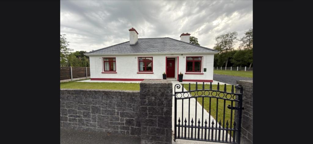 a small white house behind a stone fence at The Old Post Office Cottage in Castlebar