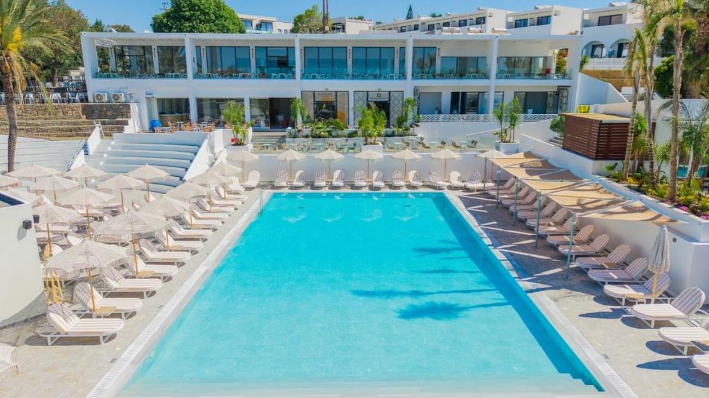 a resort pool with chairs and a hotel in the background at Aiora Aqua Resort in Pefki
