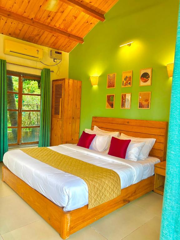 a bedroom with a large bed with green walls at Harmals Studios & Apartments in Arambol