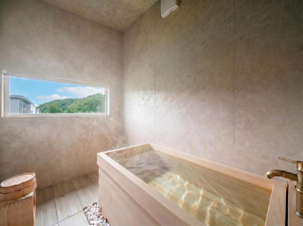 a bathroom with a bath tub with a window at Rusutsu Backcountry Lodge in Kimobetsu