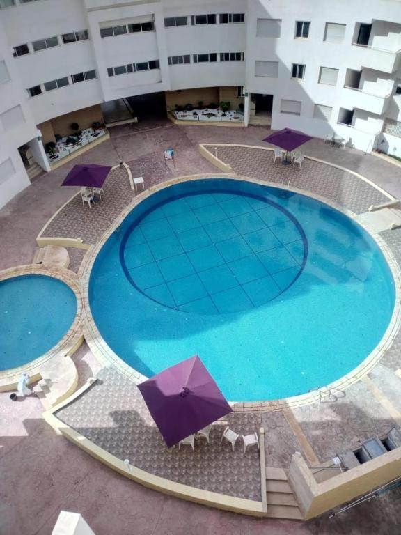 an overhead view of a large swimming pool with umbrellas at Super Appartement à Bouznika in Bouznika
