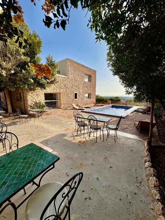 a patio with tables and chairs and a swimming pool at Chez les copains in Sidi Kaouki
